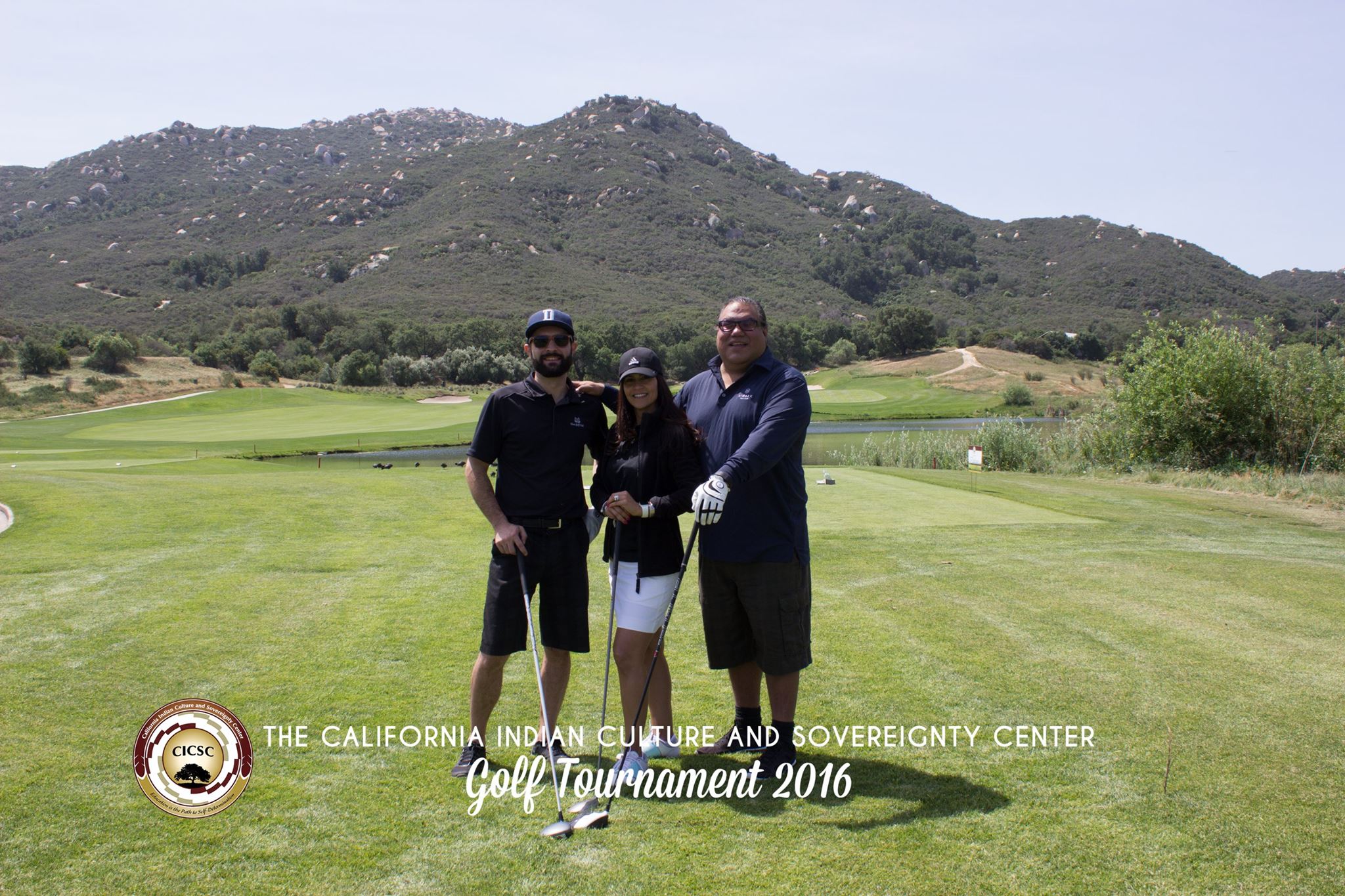 Alex Bailey, Joely Proudfit, Chris Eyre posing together on a green golf course with mountains behind in the distance and the words "The California Indian Culture Sovereignty & Center Golf Tournament 2016" at the bottom of the image with the CICSC logo