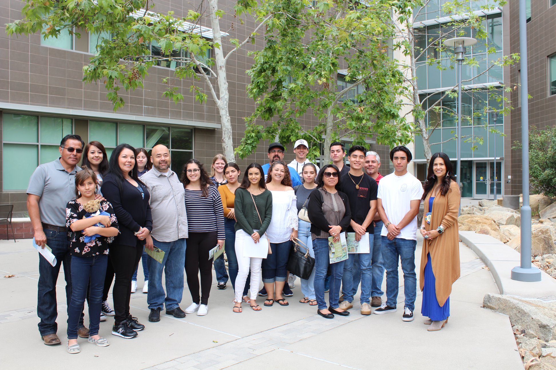 Group of parents, students, and staff standing outside in a courtyard in front of a university building