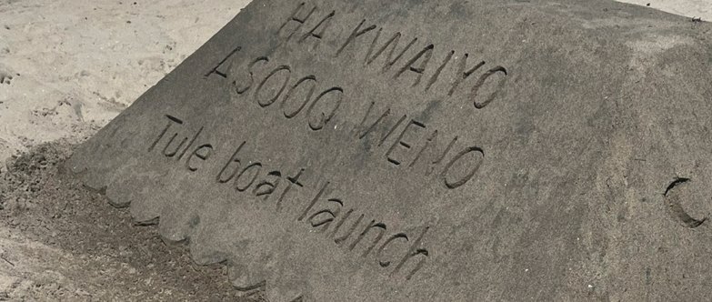 A neatly formed block of sand with the words, "HA KWAIYO ASOOQ WENO Tule boat launch" traced into its smooth surface