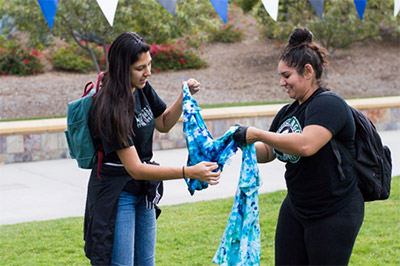 Two students apply dye to t-shirts