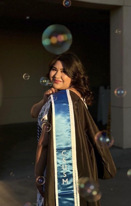 Graduation photo of CSUSM student with bubbles in the background.